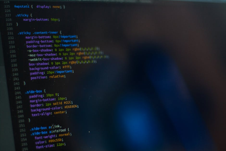 A close-up image of a computer screen displaying lines of programming code with multicolored syntax highlighting in shades of blue, pink, green, yellow, and white on a dark background. The code appear